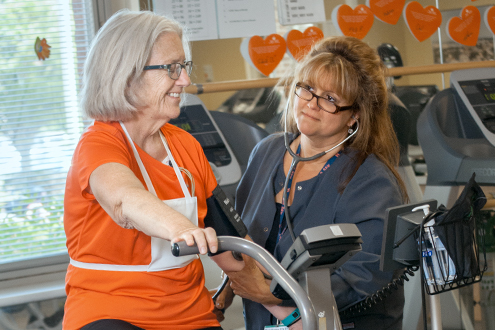 Lifespan cardiovascular patient on leg machine with physical therapist watching