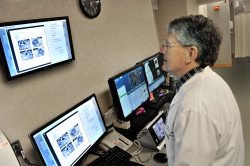 A medical technician in front of imaging screens