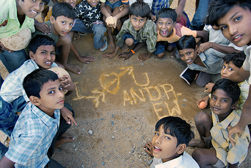 Children writing in chalk on packed earth