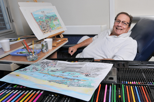 Burman sitting at his desk with art supplies
