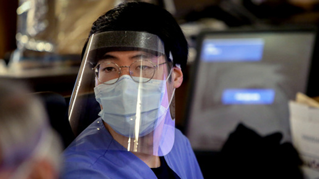 A medical staff wears a face guard.