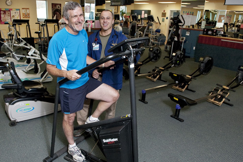 Physical therapist watches a patient use the leg machine