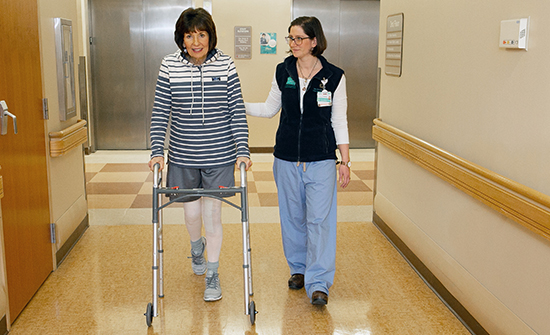 A patient walks with a physical therapist after surgery.