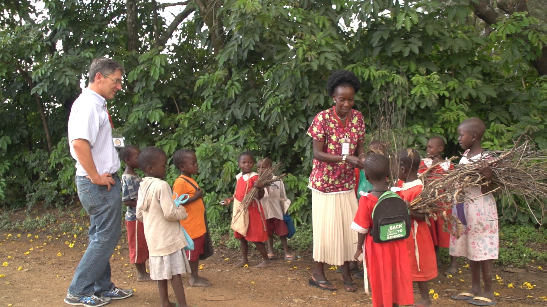 Dr. Jonathan Kurtis talks with and adult and a group of children in a rural village.