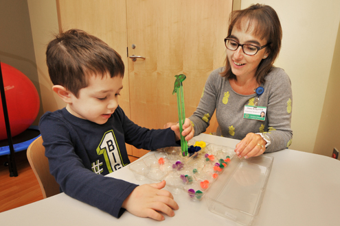 Children's Rehabilitation Therapist helps boy play a game to challenge his brain.