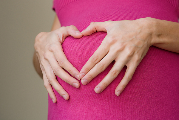 A pregnant woman's hands rest on her stomach.  Fetal Treatment Program of New England.