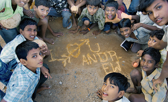 Children writing in chalk on packed earth