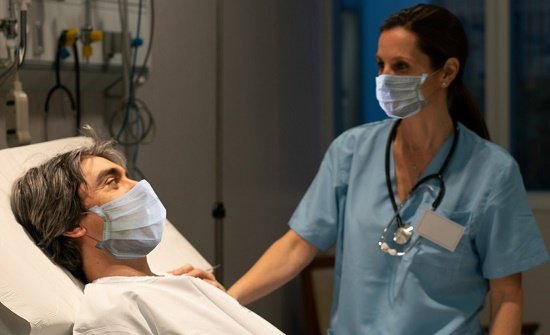 Male patient in hospital bed being seen by a female medical professional