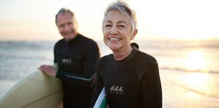 Older women and man surfing on beach