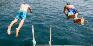Two boys diving into water from dock
