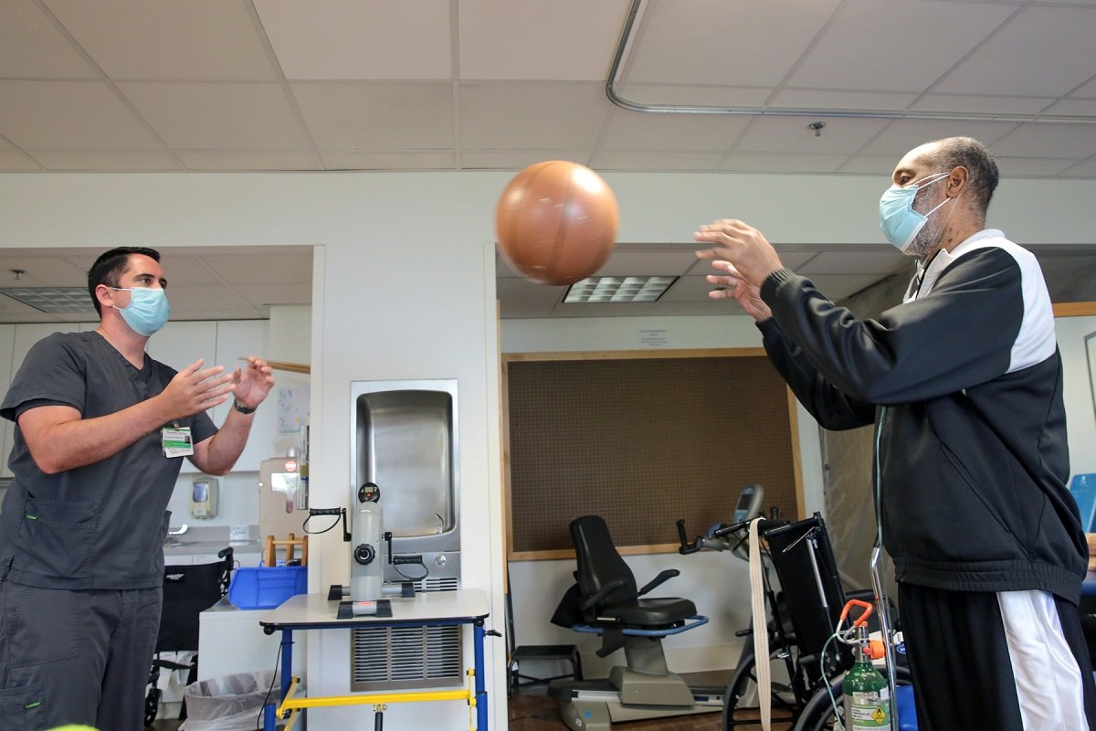Adult and staff throwing a basketball at Vanderbilt Rehabilitation Center