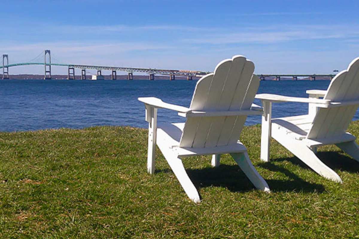 Two empty chairs with a view of Newport Bridge.