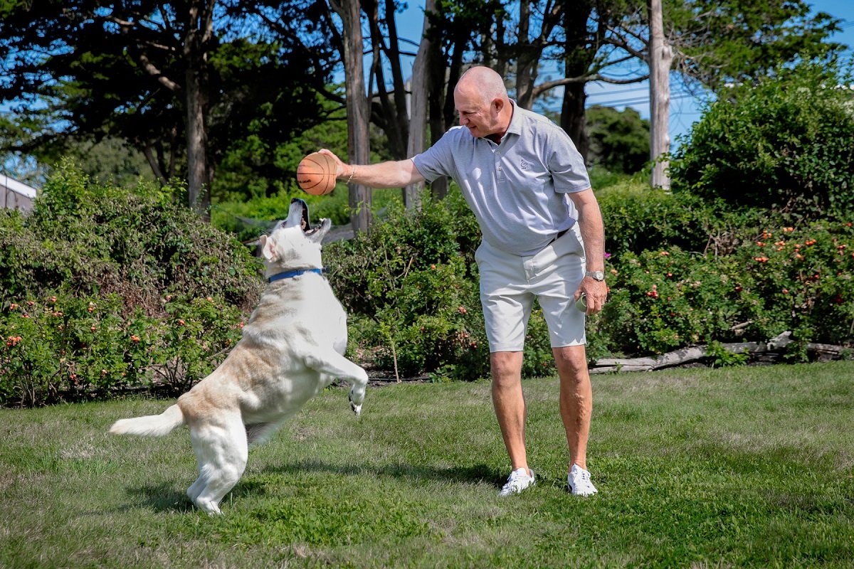 Tom Cioffi playing ball with one of his dogs in his yard.